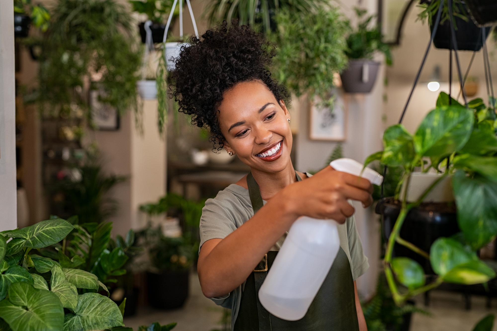 African american woman watering plants in botany shop